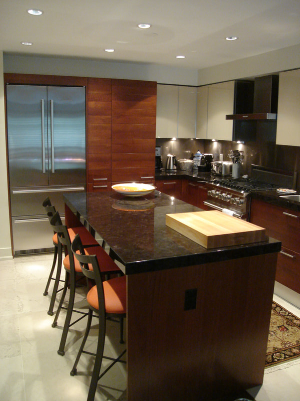 Cherry veneer kitchen with horizontal wood grains and grooves, black stone countertop, stainless appliances, built in fridge