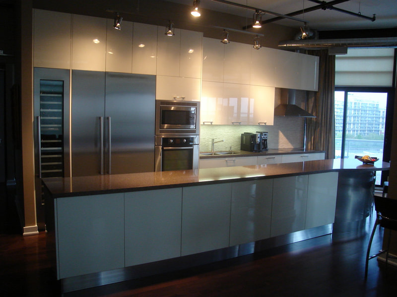 Glossy lacquer kitchen, built in wine column, built in stainless steel fridge and freezer columns, long round island